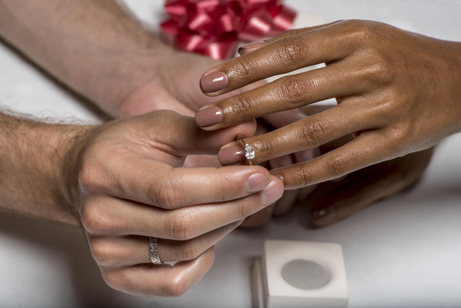 Photograph of a man placing an engagement ring on a woman's finger