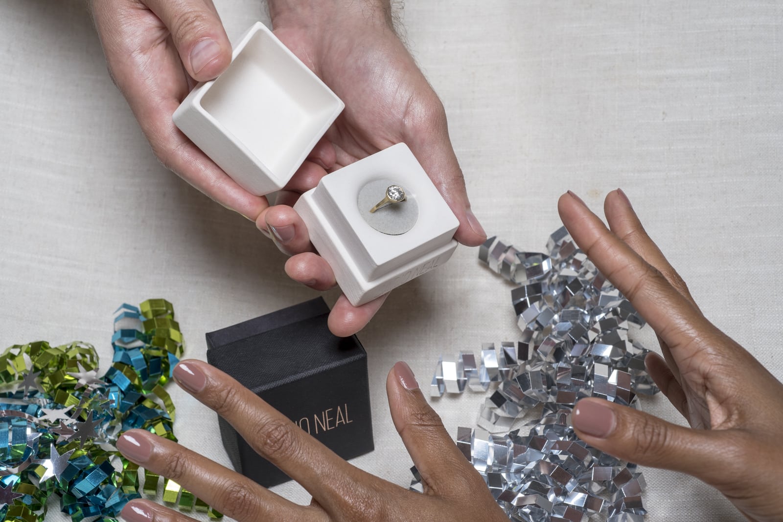 Photograph of a man holding a jewelry box with an engagement ring inside