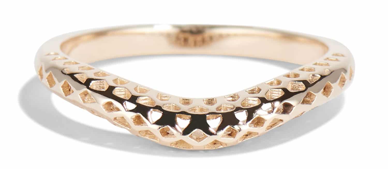 A polished gold ring with a unique V-shaped design features textured surfaces and cutouts. It rests on a neutral backdrop, showcasing its elegant craftsmanship and style.