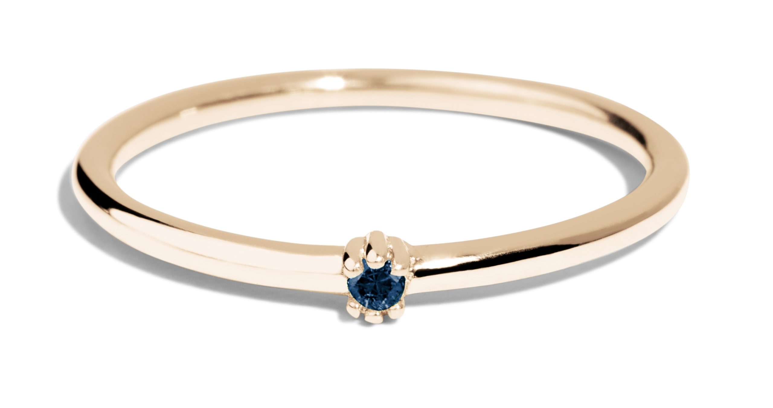 A gold ring featuring a central blue sapphire gemstone secured by a delicate claw setting. The ring is shown against a plain white background, emphasizing its smoothness and the contrast with the gemstone.