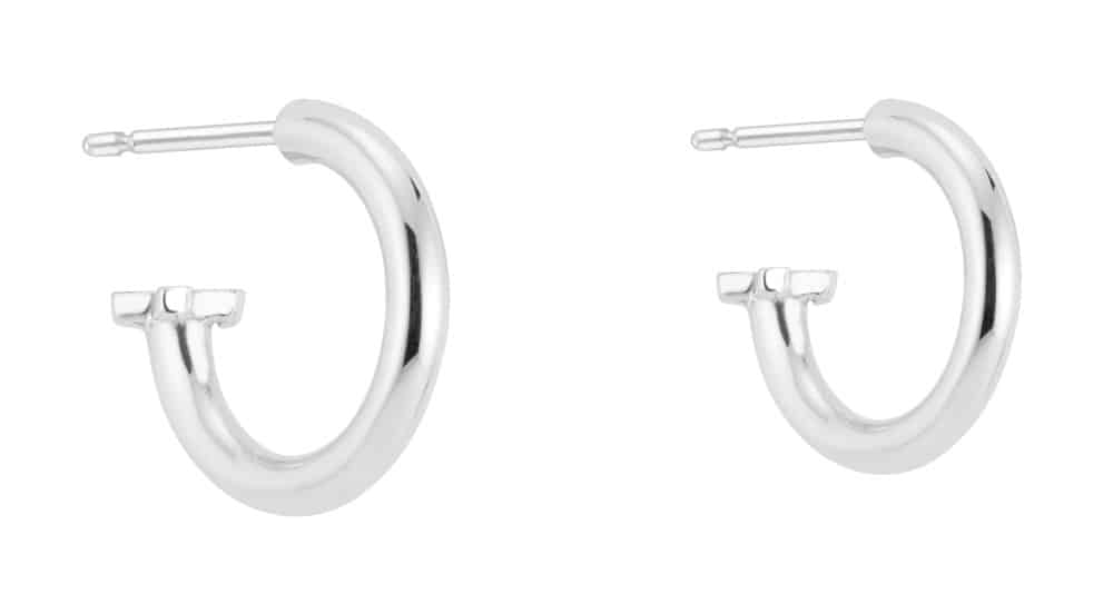 A pair of shiny silver hoop earrings is displayed, each featuring a smooth, rounded design with a subtle clasp at the end, set against a plain white background.