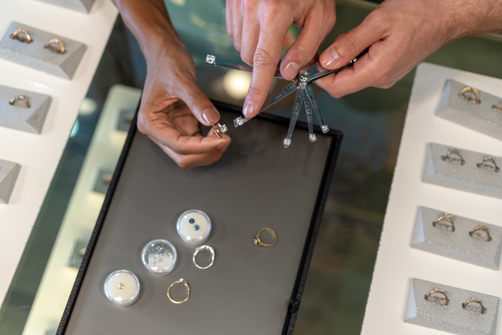 Photograph of two pairs of h ands pointing at engagement rings