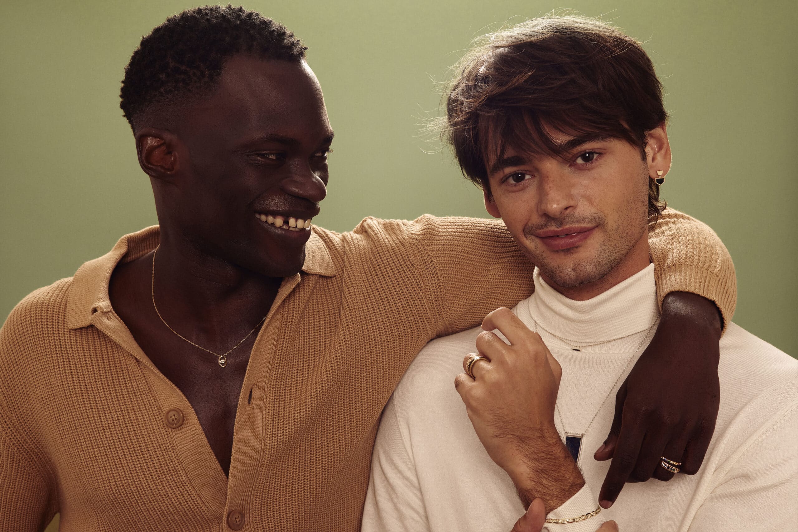 two men smiling wearing a lot of jewelry